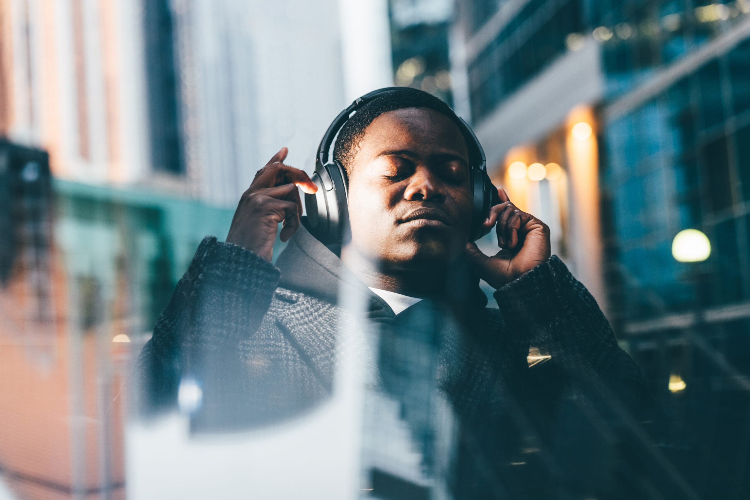 Portrait of stylish man with earphones in the city at night